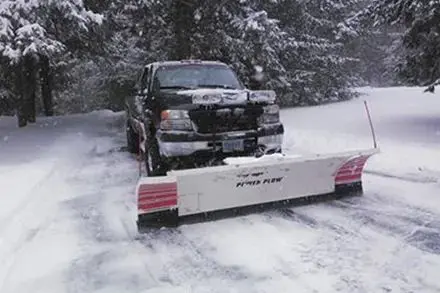A truck is plowing snow on a snowy road.